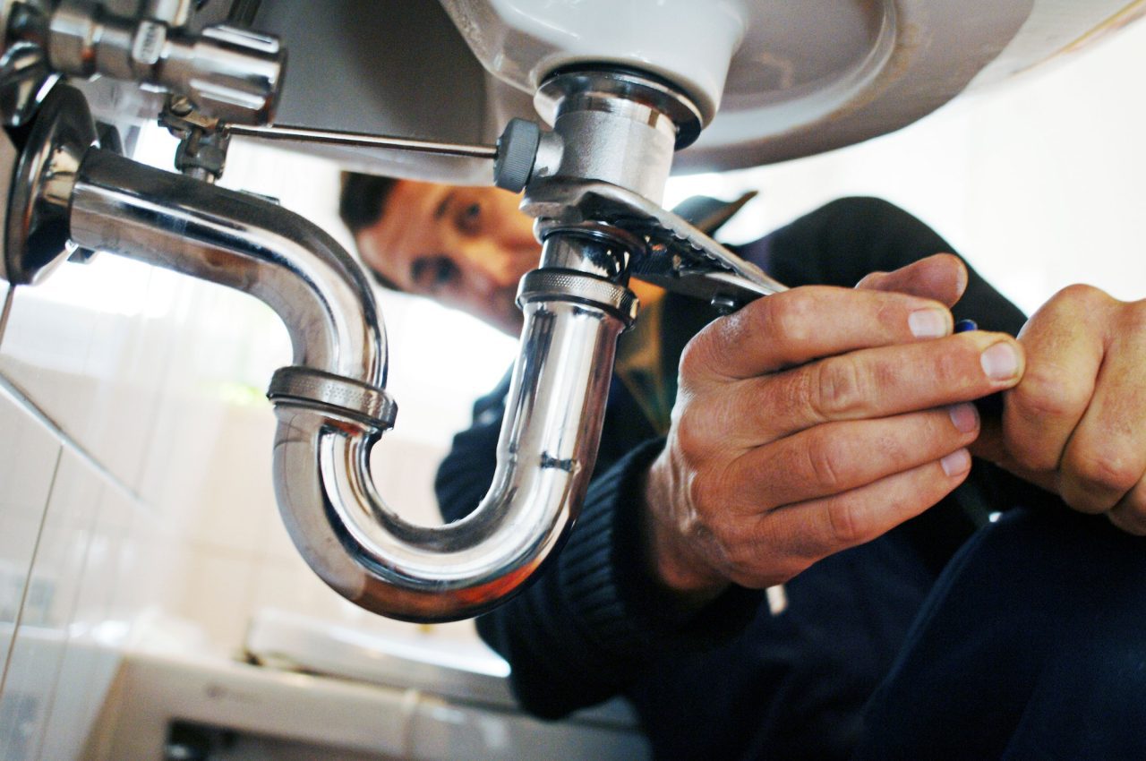 Plumber repairing a water heater leak in Astoria, NY<br>