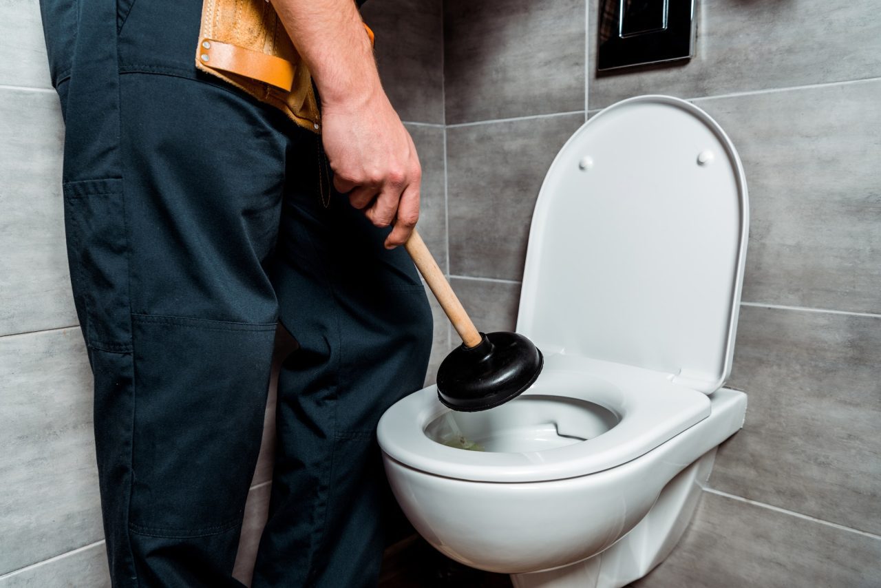 Plumber repairing a toilet in an Astoria bathroom<br>